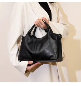 Black leather retro tote handbag detail, featuring classic stitching and dual top handles.