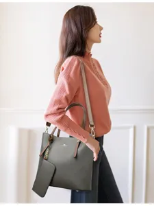 Detail view of the soft leather grey tote handbag and matching small pouch set worn on model.