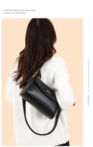 Details of the black leather shoulder bag worn by model, showing compact size and lock.