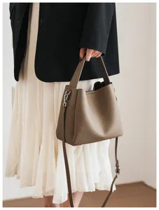 Elegant brown pebbled leather bucket bag with top handle and crossbody strap for women daily use.