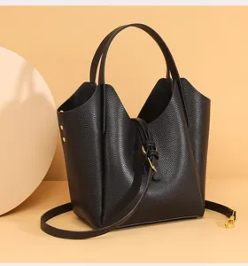 Black genuine leather bucket bag detail, litchi pattern texture with handle and strap.