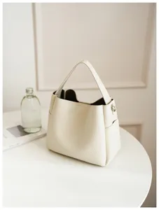 Detail view of stylish white pebble leather bucket bag, elegant lifestyle display shot.