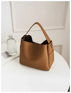 Brown soft leather bucket bag detail showing premium texture and shoulder strap design for use.
