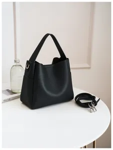 Black leather bucket bag detail showing premium texture and detachable strap on white table