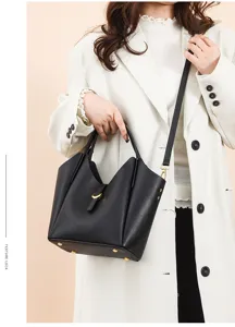 Detail shot of black genuine leather bucket bag with gold lock hardware and shoulder strap.