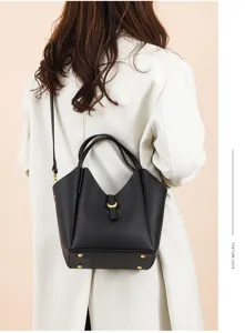 Detailed view of black genuine leather bucket bag with top handle and gold hardware.