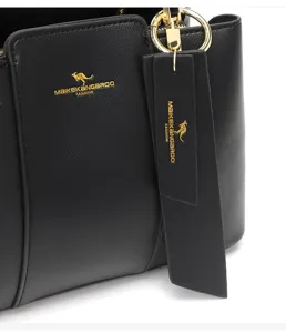 Vue détaillée du sac à main femme en cuir noir, logo doré et étiquette suspendue.