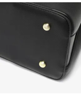 Détail du fond d'un sac à main en cuir noir avec des clous de protection dorés.