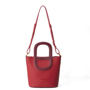 Detailansicht der roten Leder-Eimer Tasche mit kontrastierendem Griff und verstellbarem Gurt.
