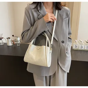 Detailed view of white soft PU leather women shoulder handbag worn by model in grey blazer.