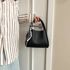 Black PU leather bucket handbag for women, stylish shoulder bag with cute heart print scarf detail.