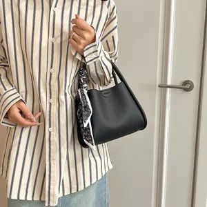 Detail view of black PU leather bucket bag with cute scarf accessory and embossed text.