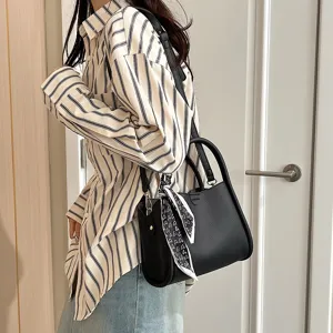 Close-up detail of the black PU leather shoulder bag featuring a chic printed scarf handle.