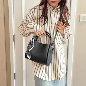 Detail view of black PU leather shoulder bag with chic scarf and handle for women.