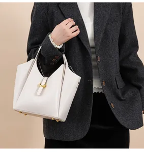 Genuine leather bucket handbag for women, elegant beige shoulder bag with chic clasp detail.
