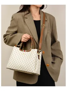 Detailed view of the elegant women's patterned shoulder handbag with brown leather handles.