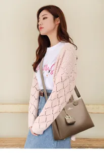 Detailed view of women's brown leather tote handbag featuring a metal lock pendant charm.