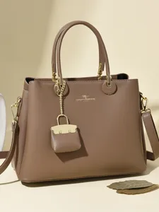Stylish brown leather tote bag with top handles, shoulder strap, and cute mini charm.