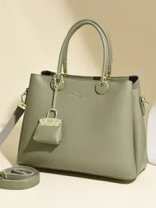 Stylish green leather tote bag with top handles, crossbody strap and cute mini charm for women.