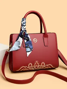 Red stylish leather handbag with exquisite embroidery and chic scarf decor for women.