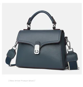 Leather handbag detail showing grey-blue cowhide, metal lock, and elegant shoulder strap.