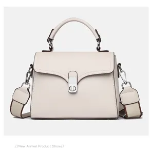 Detail view of the elegant beige cowhide handbag featuring structured top handle and metal lock.