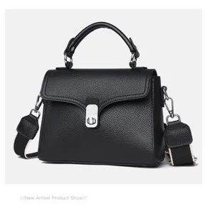 Detailed view of black leather top-handle crossbody bag with metallic turn-lock and strap.