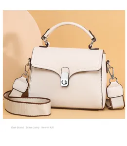 Detailed view of genuine leather handbag with metal turn-lock closure and brown piping.