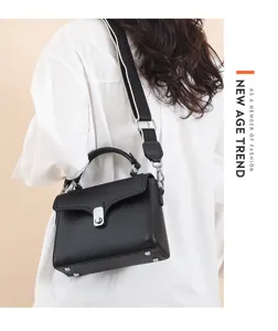 Detail view of the black leather crossbody bag featuring a wide woven strap and secure metal lock.