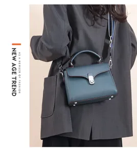 Leather top handle bag detail showcasing premium texture, metal lock and structured square shape.