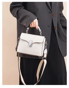 Genuine leather top handle crossbody bag detail, featuring metal lock closure and wide strap.