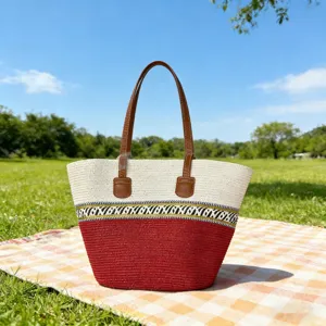 Detailansicht der Strohtasche im Boho-Stil mit rot-weißem Muster und braunen Ledergriffen.