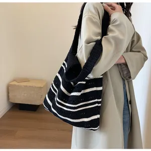 Detailed view of the black and white striped crochet shoulder bag carried by a model indoors.
