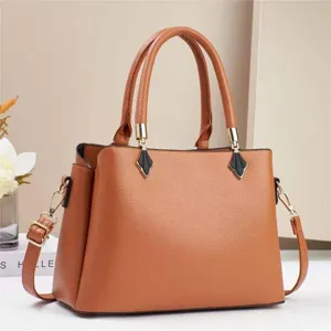 Detailed view of the brown leather commuter handbag showing golden hardware and handle design.