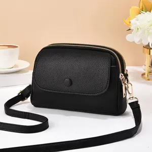 Détail de sac bandoulière noir pour femmes avec doubles compartiments zippés et quincaillerie dorée.