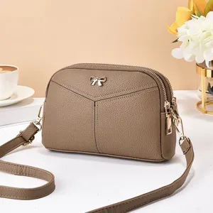 Vue détaillée du sac bandoulière en cuir kaki, orné d'un nœud en métal et de doubles zips.