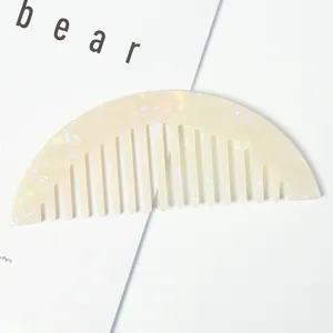Vue détaillée du peigne à cheveux à dents larges en acétate avec une finition marbrée irisée.