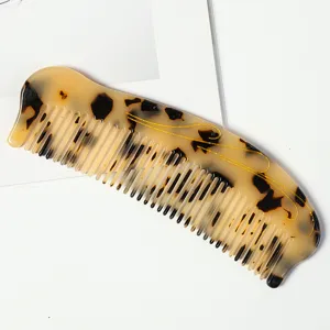 Peigne à cheveux fin en acétate motif écaille marbré avec détails de lignes dorées.