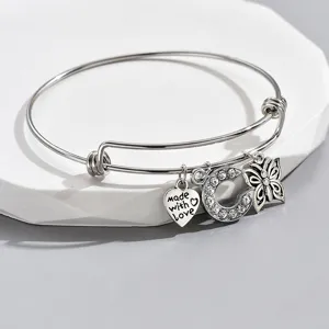 Close-up of silver expandable charm bracelet with rhinestone letter C, heart, and butterfly.