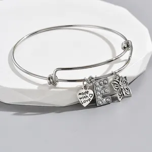 Adjustable silver wire bangle bracelet with heart rhinestone letter E and butterfly charms.