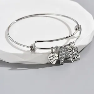 Detailed shot of silver adjustable charm bracelet with rhinestone letter F heart butterfly.