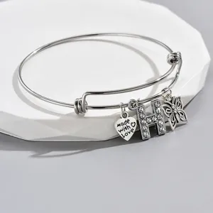 Close-up of adjustable silver wire bracelet featuring sparkling rhinestone letter H, heart and butterfly.