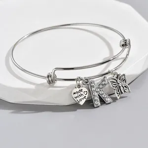 Adjustable silver wire bangle bracelet with rhinestone letter K, butterfly and heart charms.