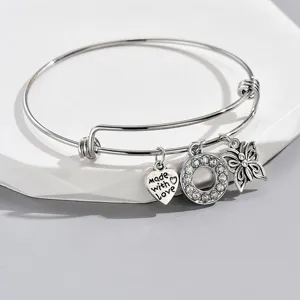 Close-up detail of silver adjustable bangle bracelet featuring cute charms like heart.