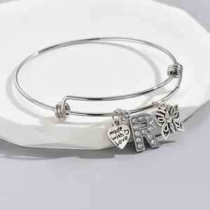 Adjustable silver wire bangle with rhinestone letter R, heart and butterfly charms.