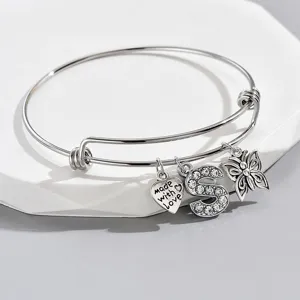 Detail view of silver wire bangle with sparkling rhinestone letter S and butterfly charms.