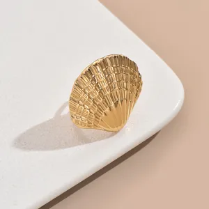 Gros plan sur la bague coquillage dorée, texture en acier inoxydable style marin.