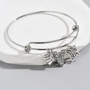 Adjustable silver bangle bracelet featuring rhinestone letter V charm, heart and butterfly.
