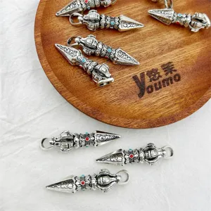 Detail shot of vintage silver alloy Vajra pestle DIY charm pendant with retro carved Buddhist motif.