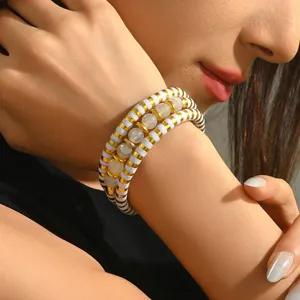 Gros plan d'un bracelet de perles multicouche avec des perles dorées et des pierres claires.
